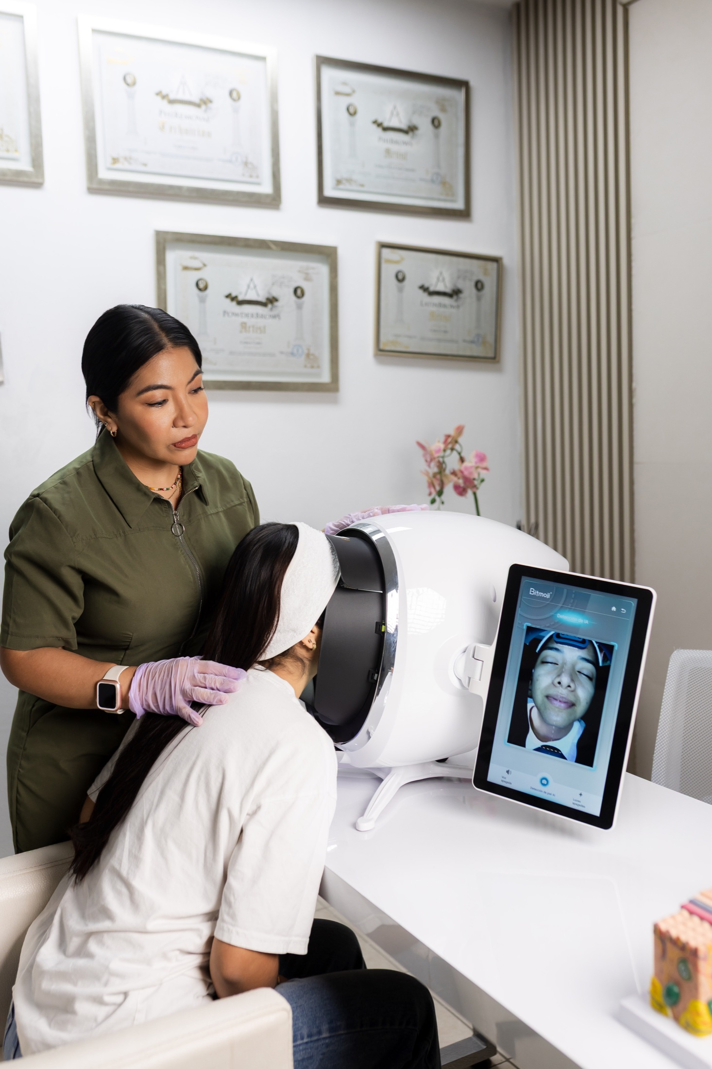 Carla Caro realizando un diagnóstico facial frente a sus certificados profesionales